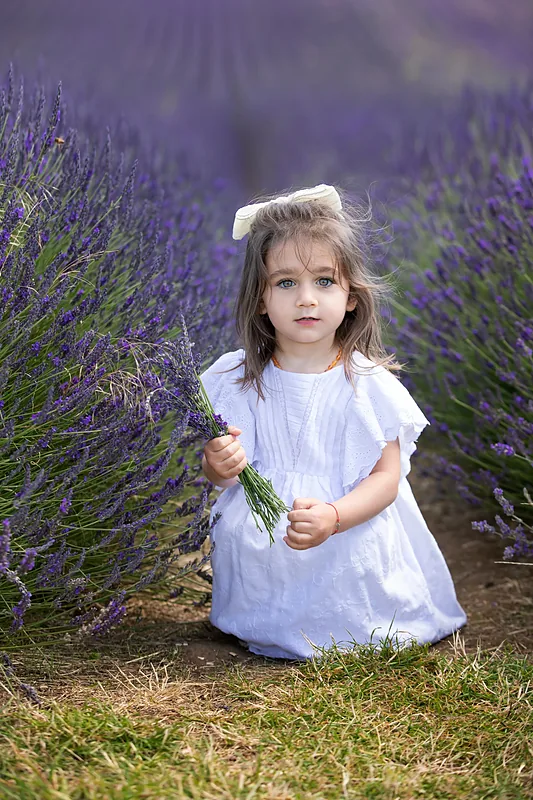 Girl in a white dress crouching in a lavender field