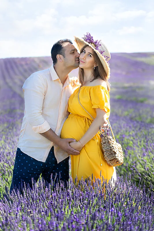 Expectant couple in a lavender field, the woman in a yellow dress and hat