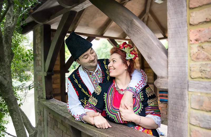 Couple in traditional embroidered costume inside a wooden gazebo