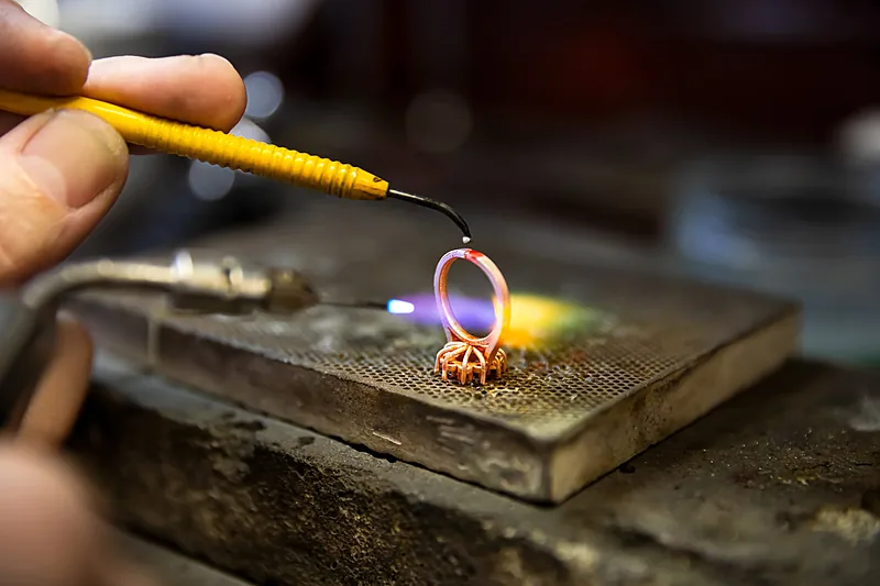 Jeweller soldering a ring with a torch on a workbench