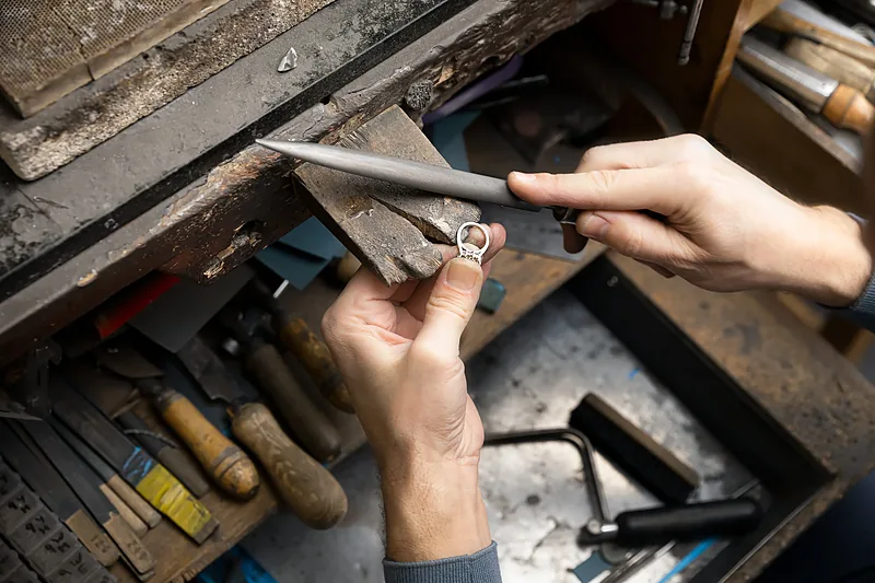 Jeweller working at a bench surrounded by tools
