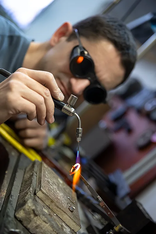 Jeweller in protective glasses using a torch at a workbench