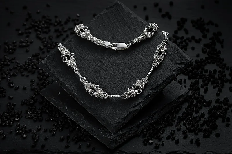 Silver necklace on a black slate against a dark background