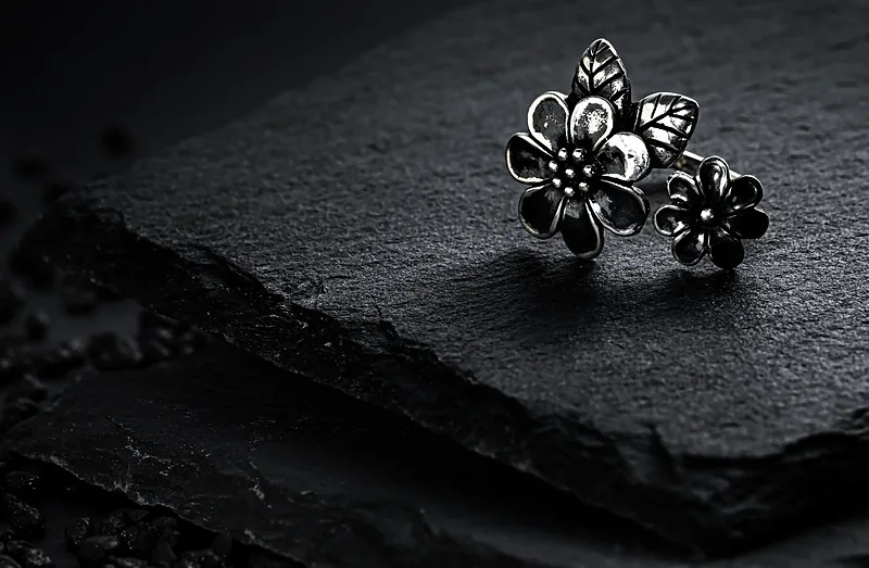 Two silver flower rings on black slate