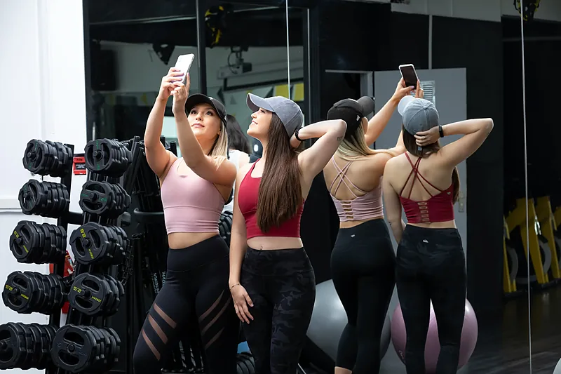 Three women in sportswear photographed from behind in a gym