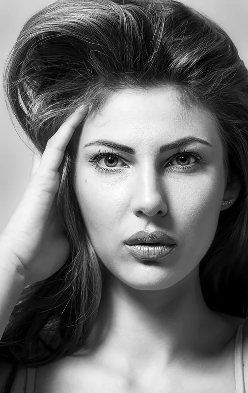 Black and white close-up portrait of a woman with a hand to her temple