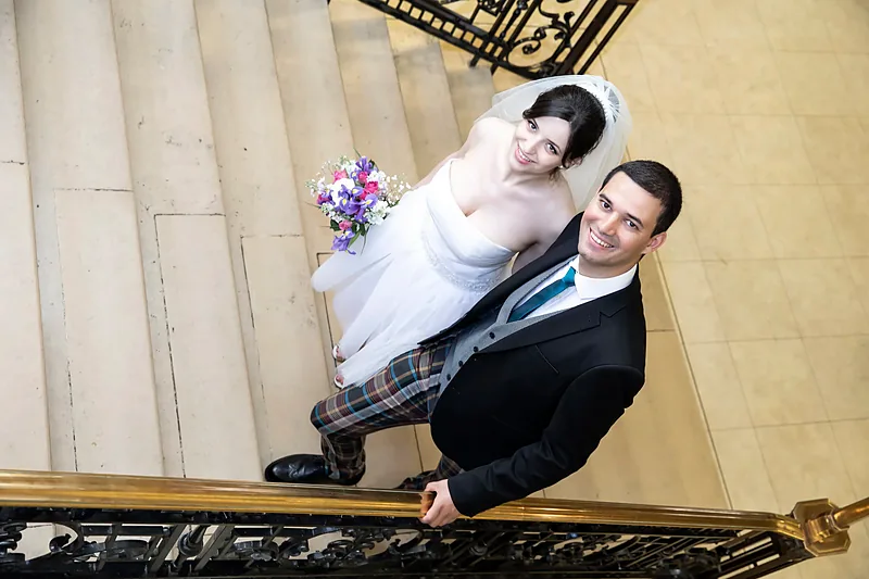 Bride and groom on a grand stone staircase, photographed from above