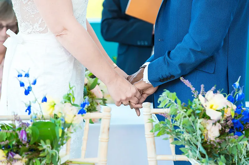 Close-up of the couple's hands during the ceremony with flowers in the foreground