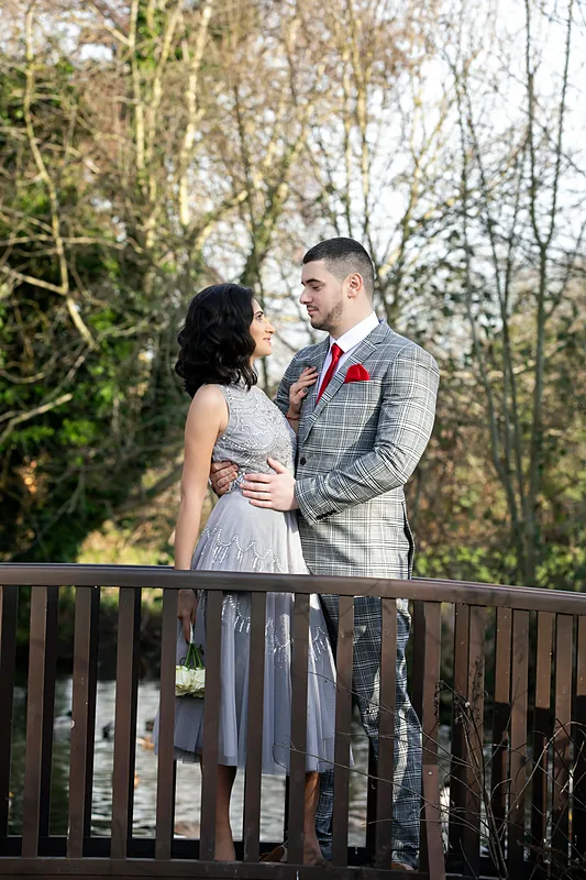 Bride and groom embracing on a wooden bridge in a park