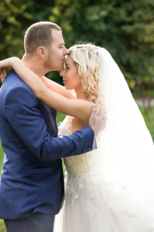 Bride and groom in a blue suit embracing outdoors